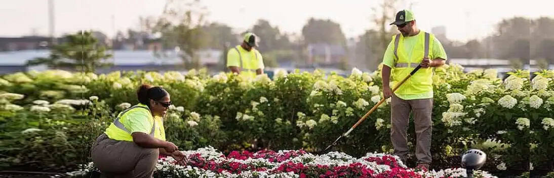 R.M. Landscape crew members performing commercial landscape maintenance, planting, and landscape bed care for a commercial property.